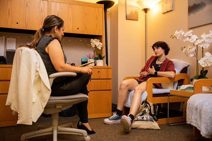 Female students sits with a counselor in an office.
